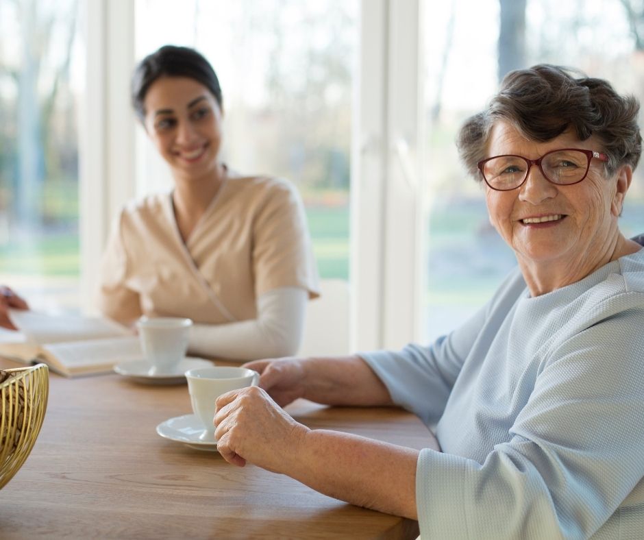 young woman having coffee and reading with senior woman