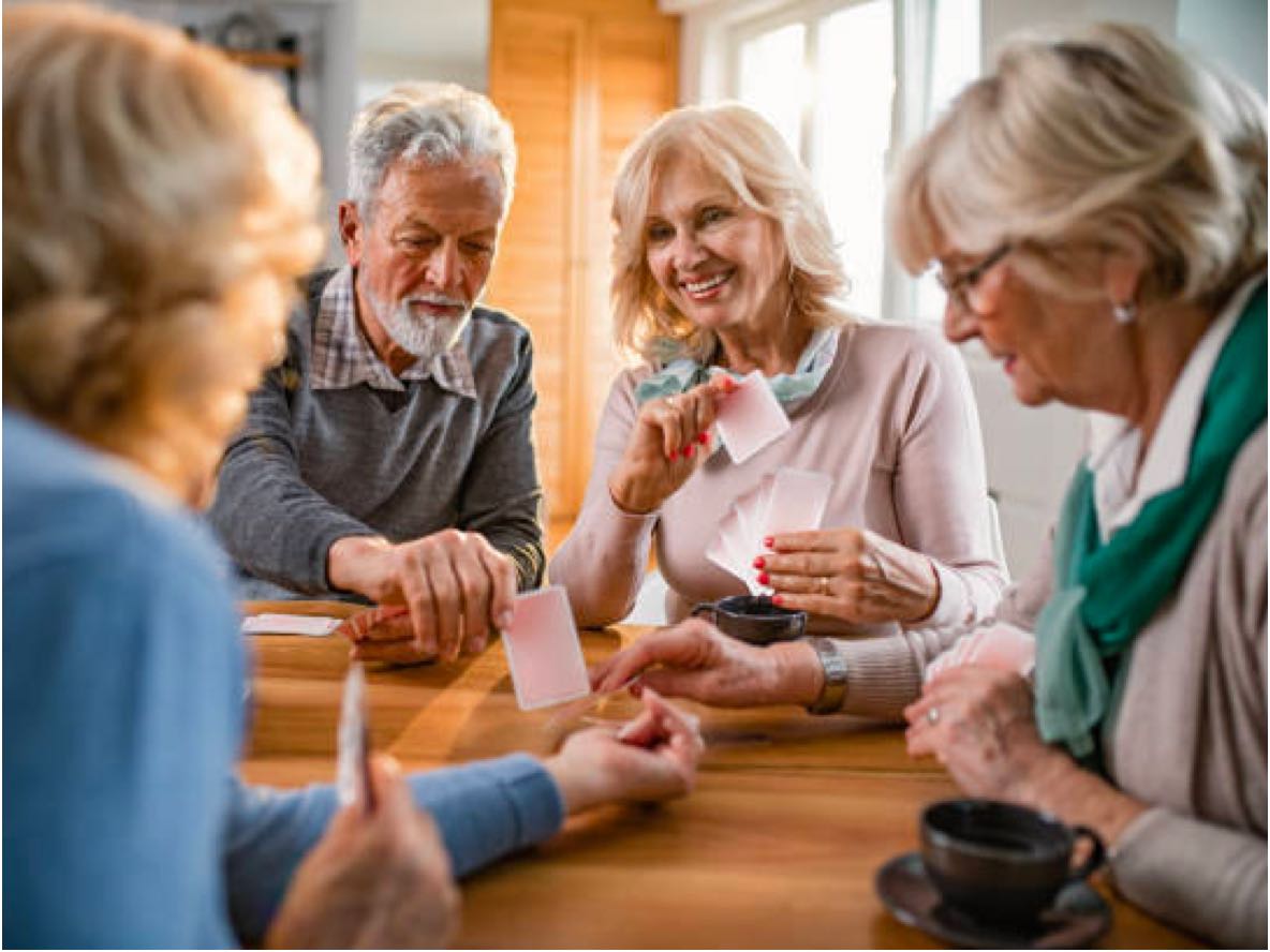 group of seniors playing cards and having coffee or tea