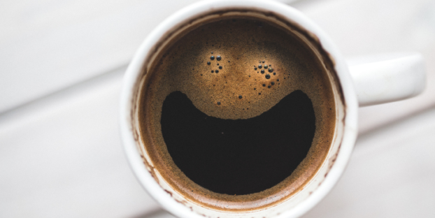 Coffee in white mug with smiley face made out of coffee foam